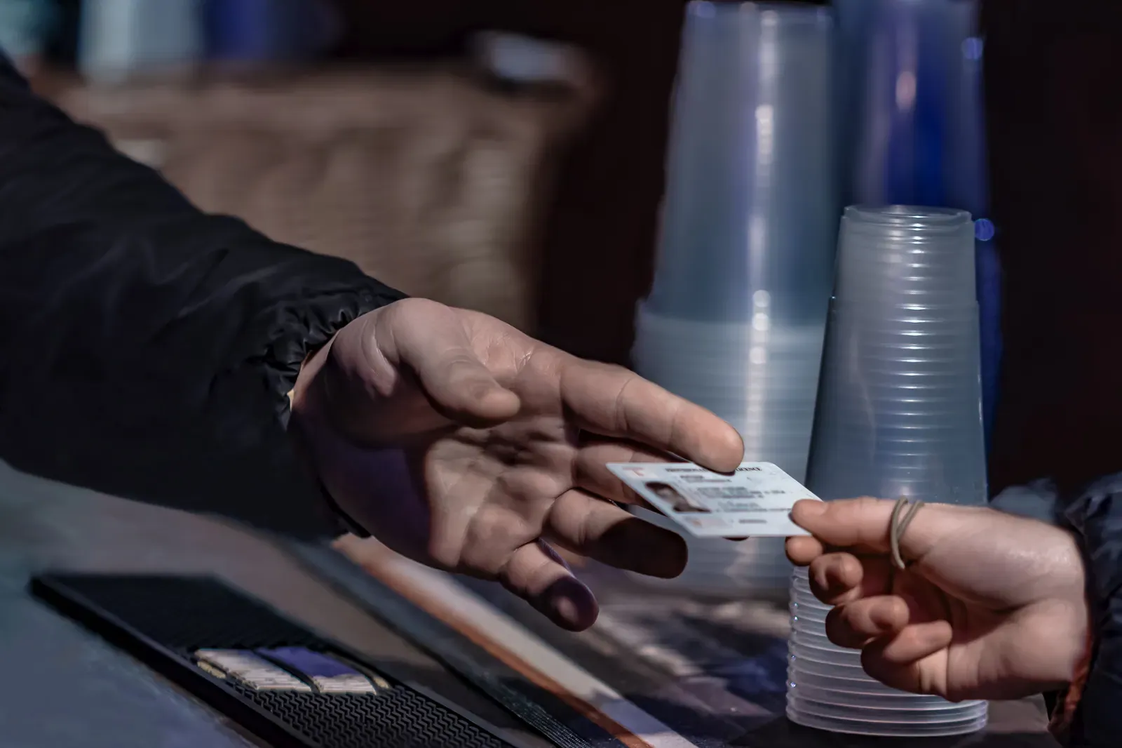 Young man show valid ID to buy alcohol and cigarettes in pub photographed with shallow depth of field