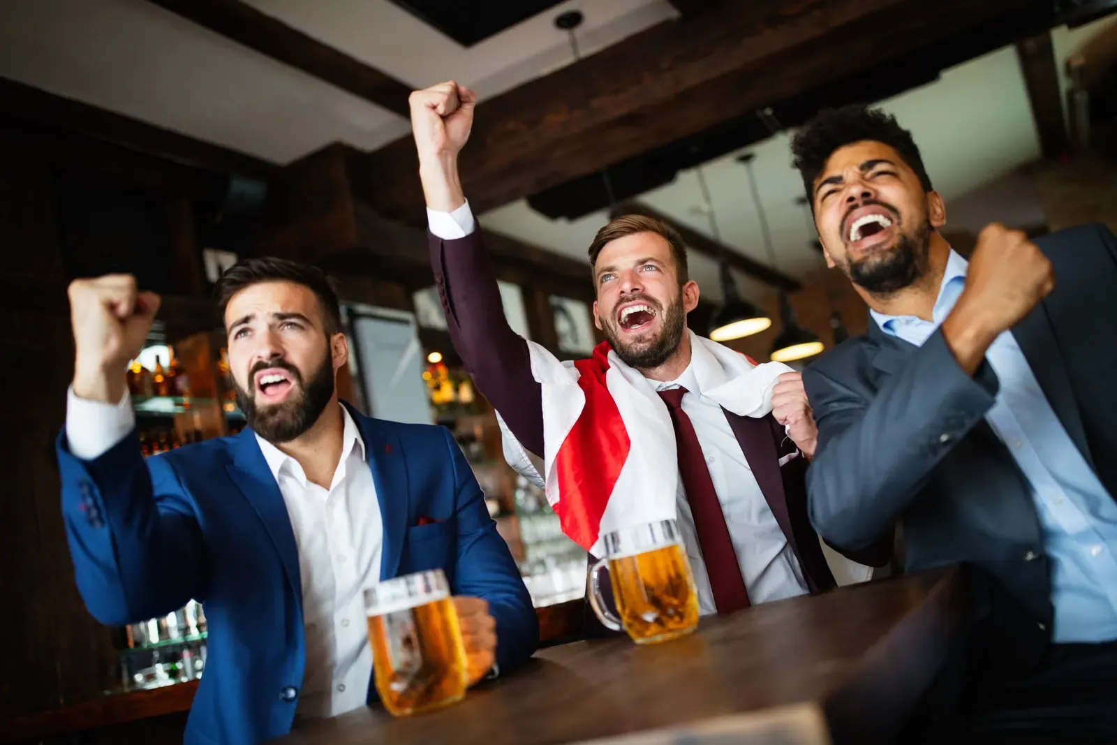 Handsome business men in pub cheering for a sporting event