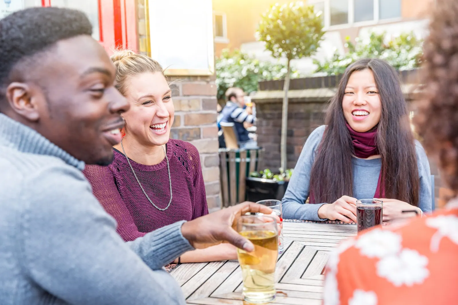 Happy multiracial friends enjoying drink together – Friendship lifestyle concept with young people spending time together at pub in London – Black, asian and caucasian people