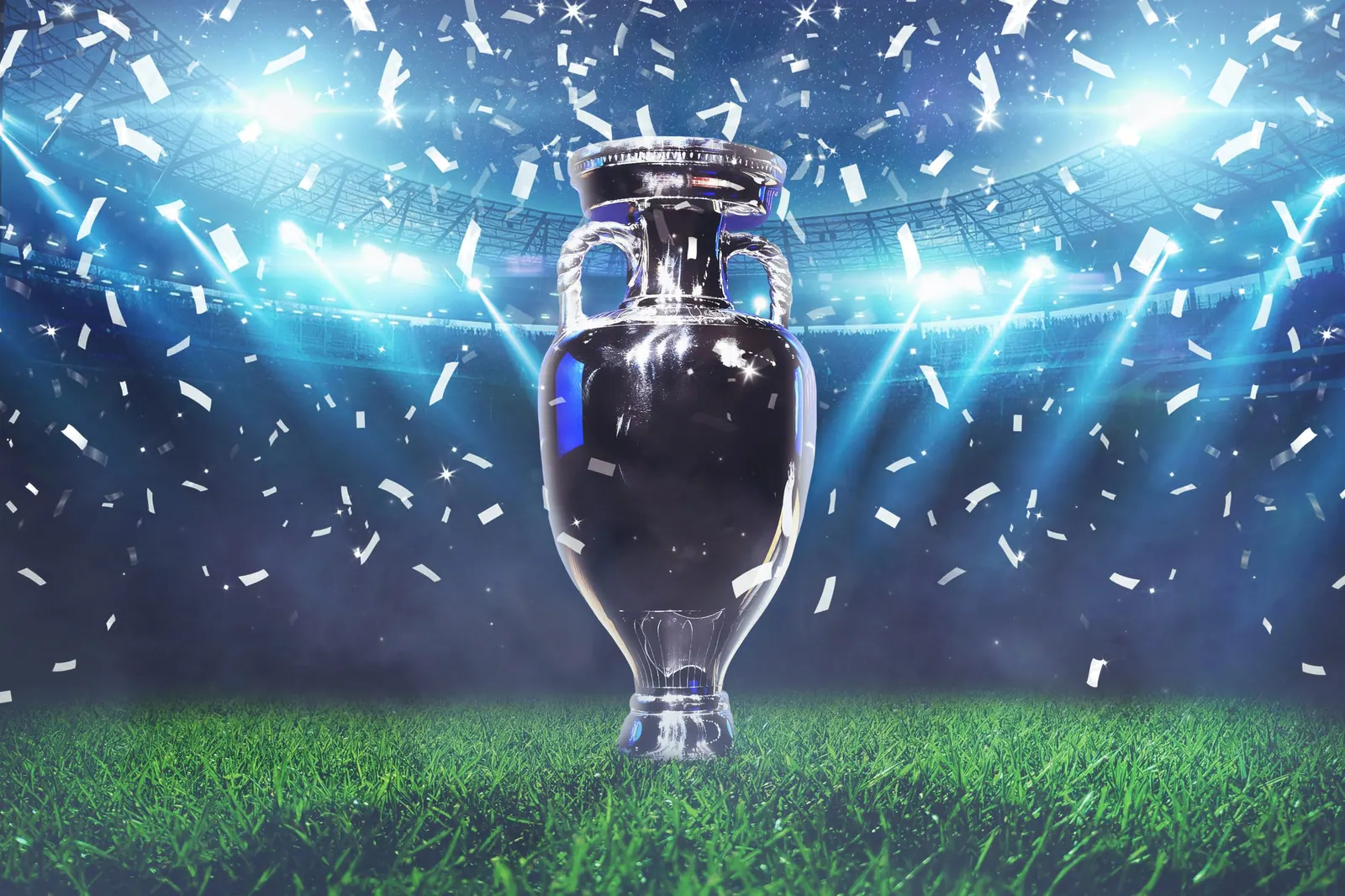 The champion cup stands on a green field at a football stadium with the light of spotlights and confetti. Football cup final, creative idea. Euro 2024 celebration